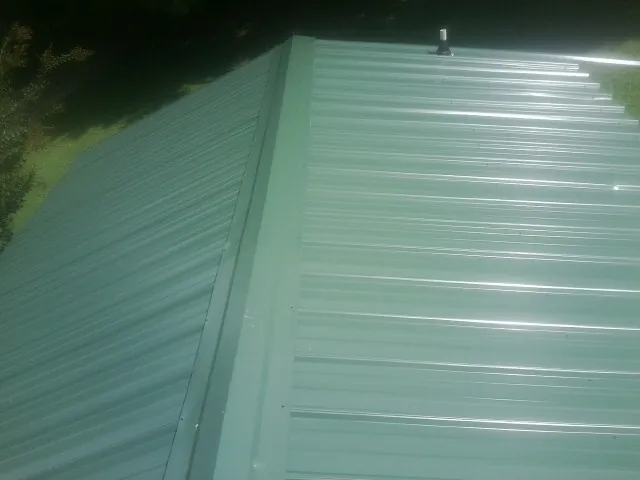 New green metal panels meeting at the ridge of a roof — Flat Roof Repair work by our crew in Grand Island