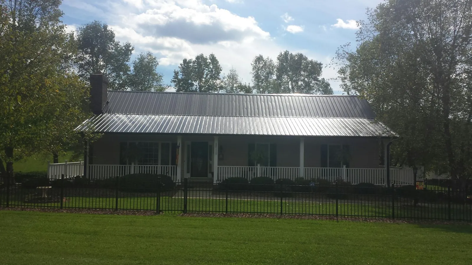 Gray metal roof on a brick ranch with a full width front porch — Gutter Guard Installation work by our crew in Grand Island