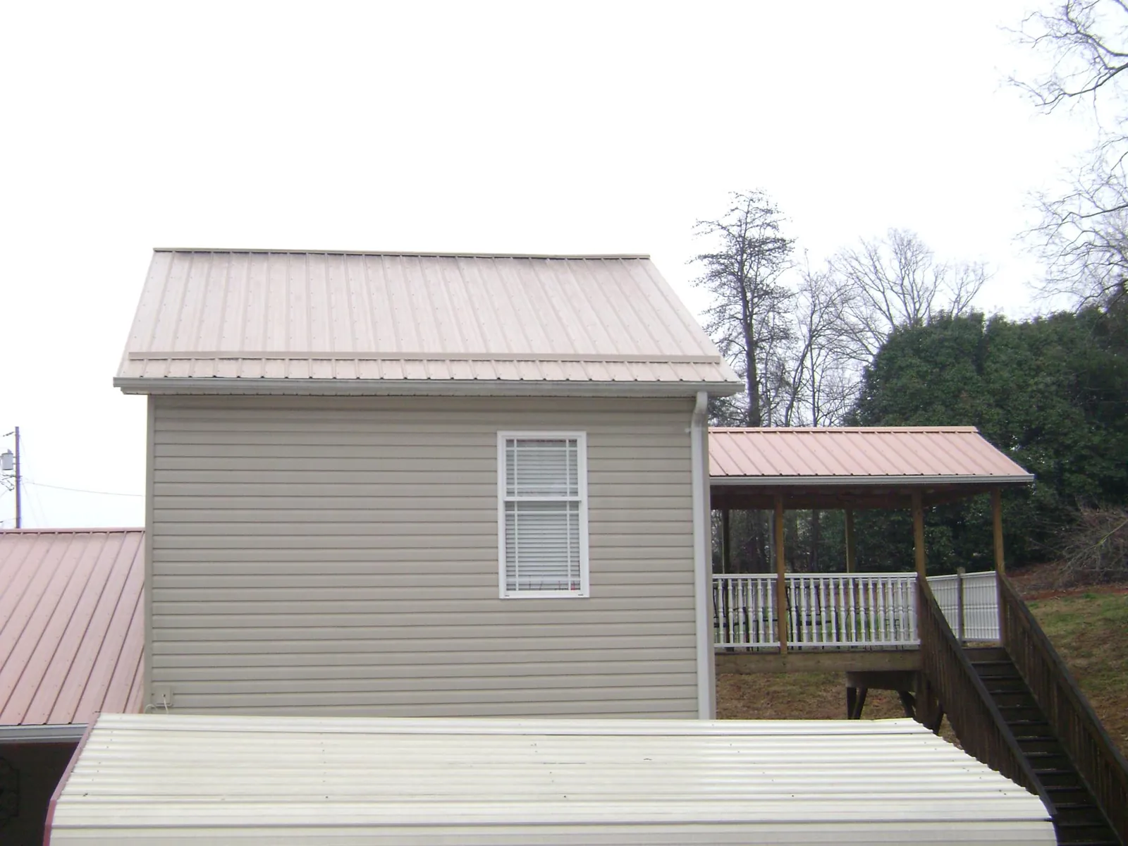 Tan metal roofs on a two story addition and attached porch, from a Roof Replacement job in Grand Island
