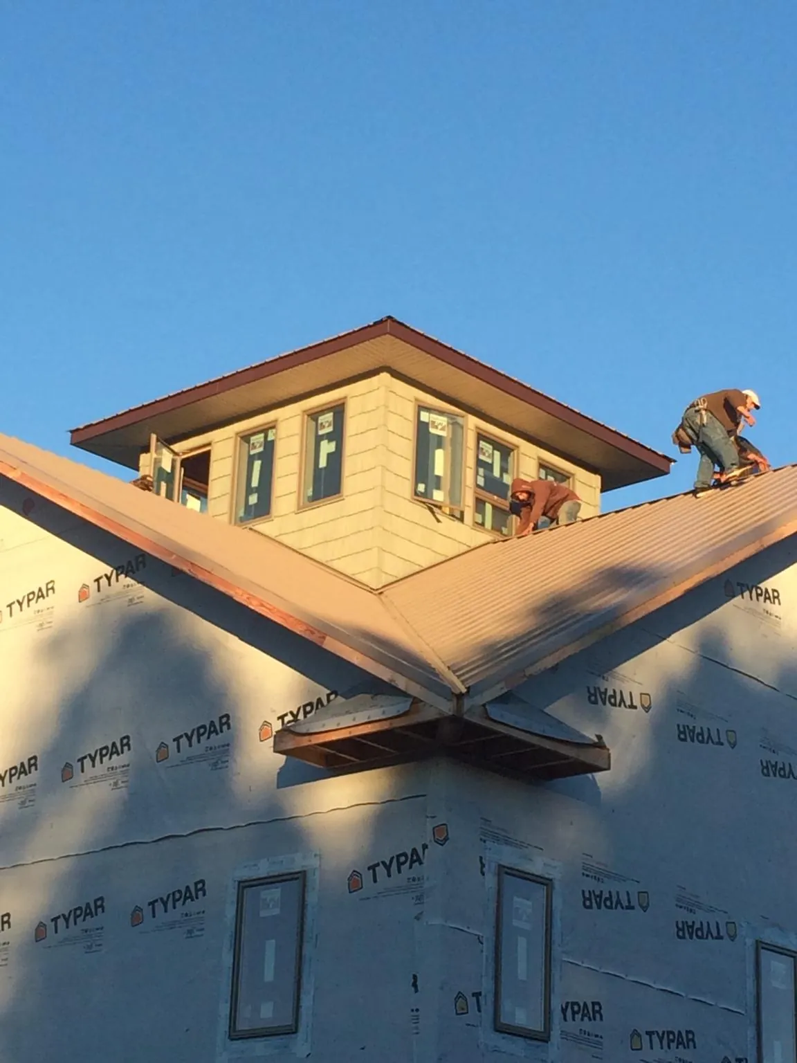 Roofers working around a rooftop cupola on a new metal roof at sunset — Roof Waterproofing in Grand Island by Roofing Brothers